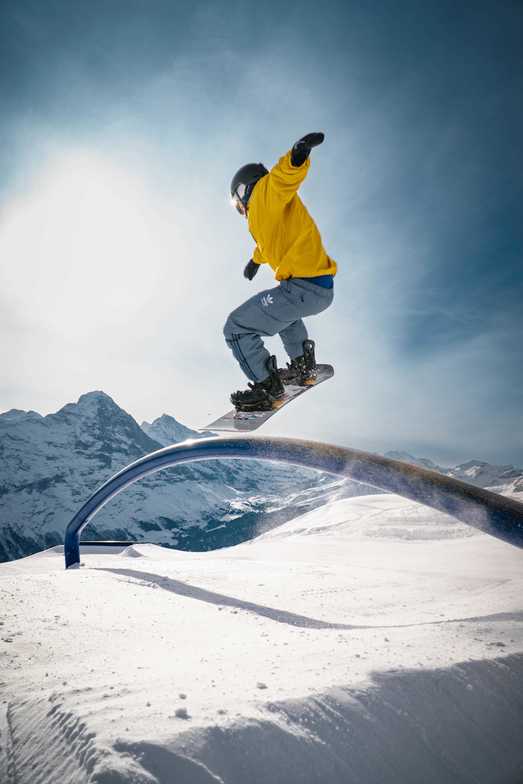 Snowboarder jumping over a railing on the mountain
